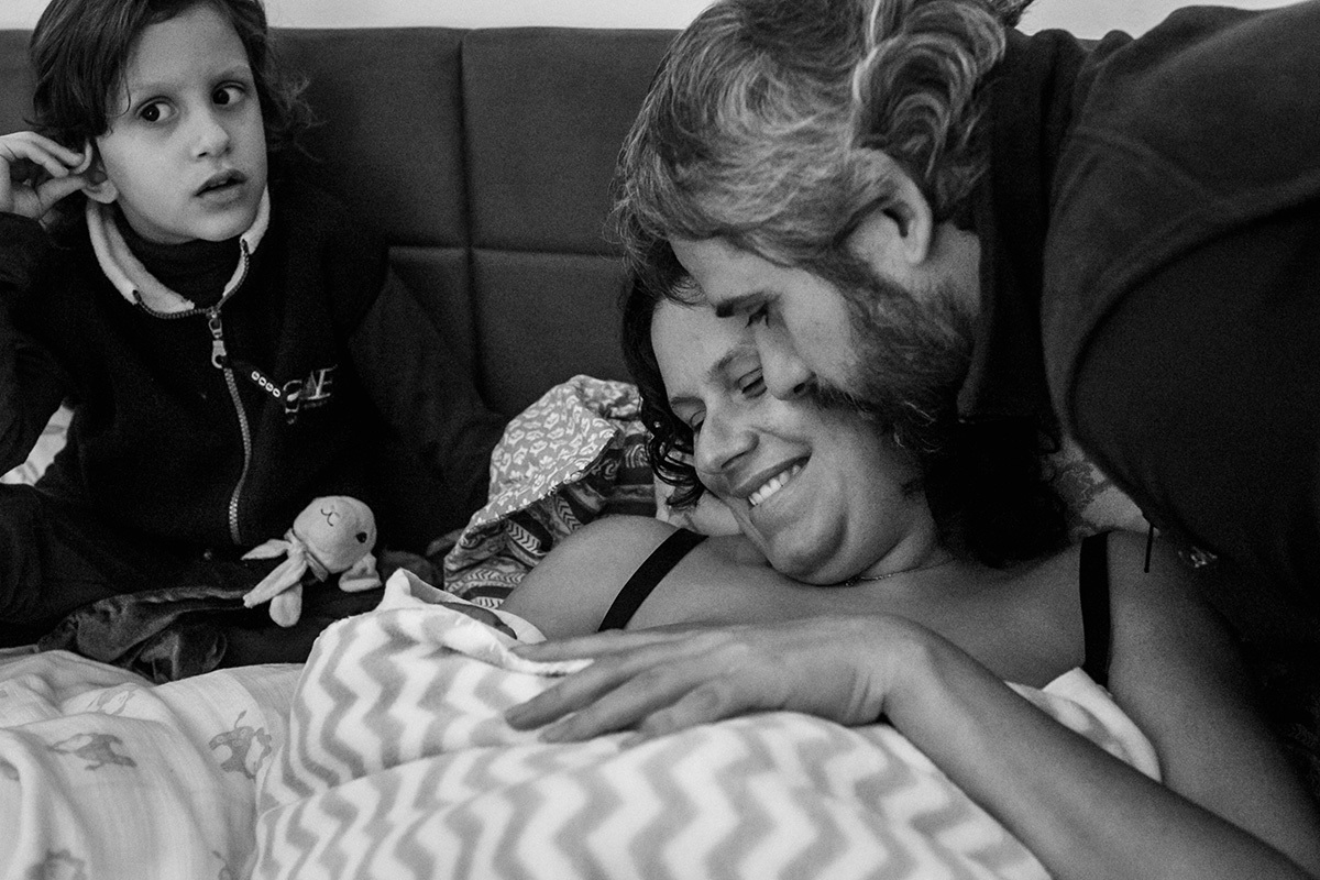 Adriana Costa fotografou casal admirando seu bebê que acabou de nascer ao lado de seu outro filho