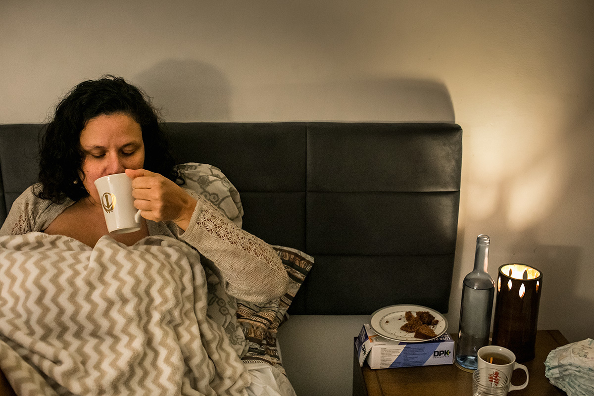 mulher alimentando logo após o parto enquanto seu bebê amamenta, por Adriana Costa