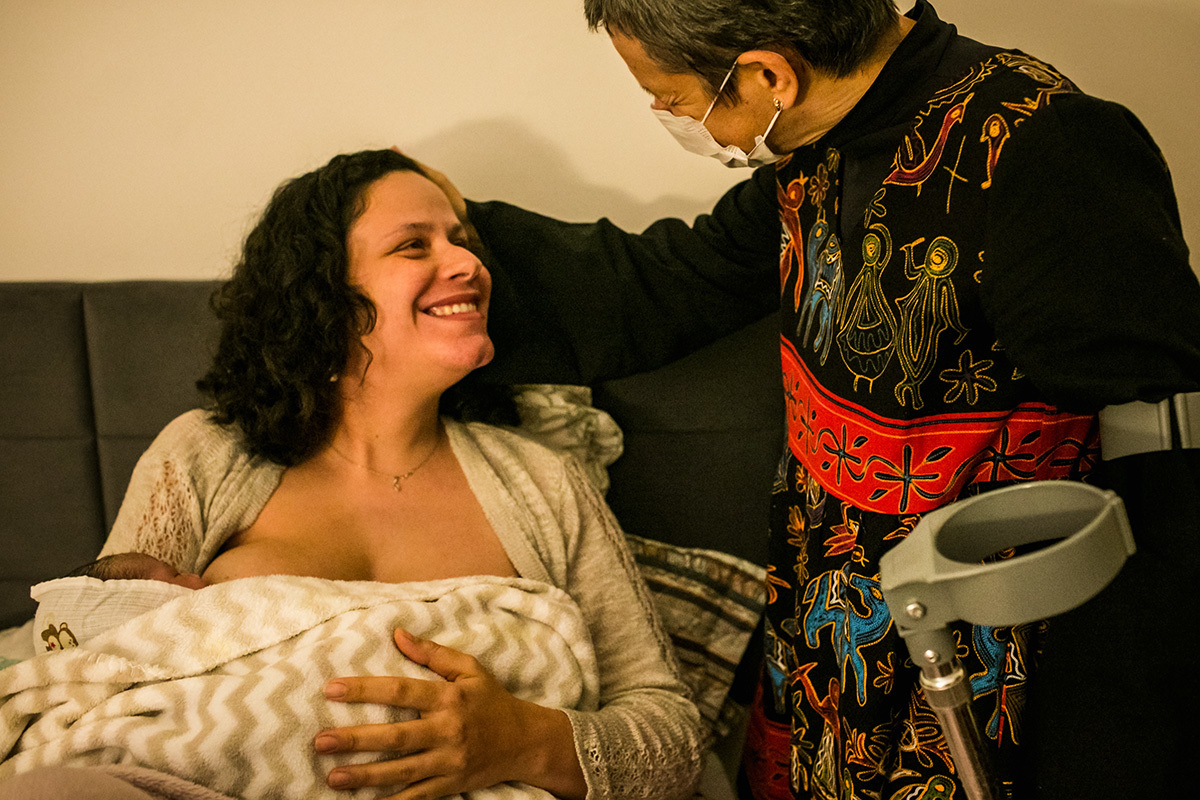 enfermeira obstetra conversa carinhosamente com a mulher que acabou de ter seu bebê