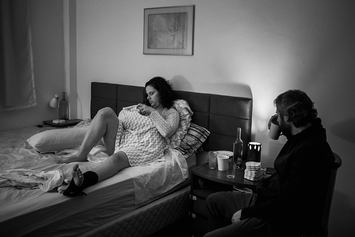 casal em seu quarto num momento de tranquilidade após o nascimento do filho que ocorreu em uma assistência de parto domiciliar, por Adriana Costa