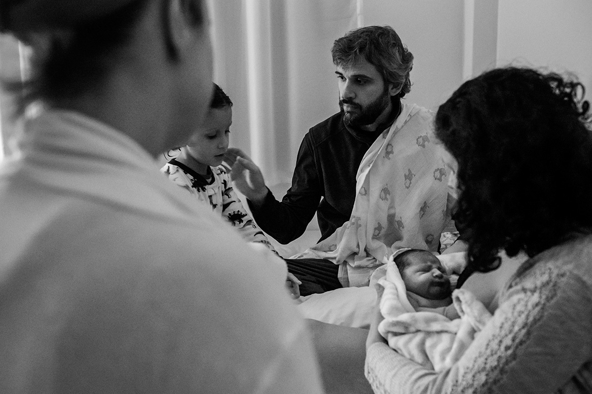 família reunida próxima ao bebê que nasceu