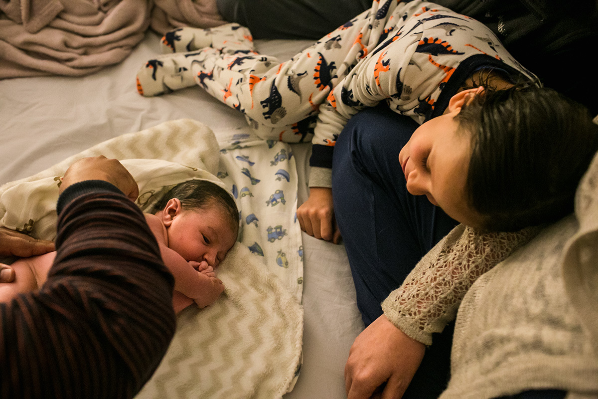 bebê recebendo seu primeiro exame após nascimento ao lado de seu irmão, em uma foto de Adriana Costa