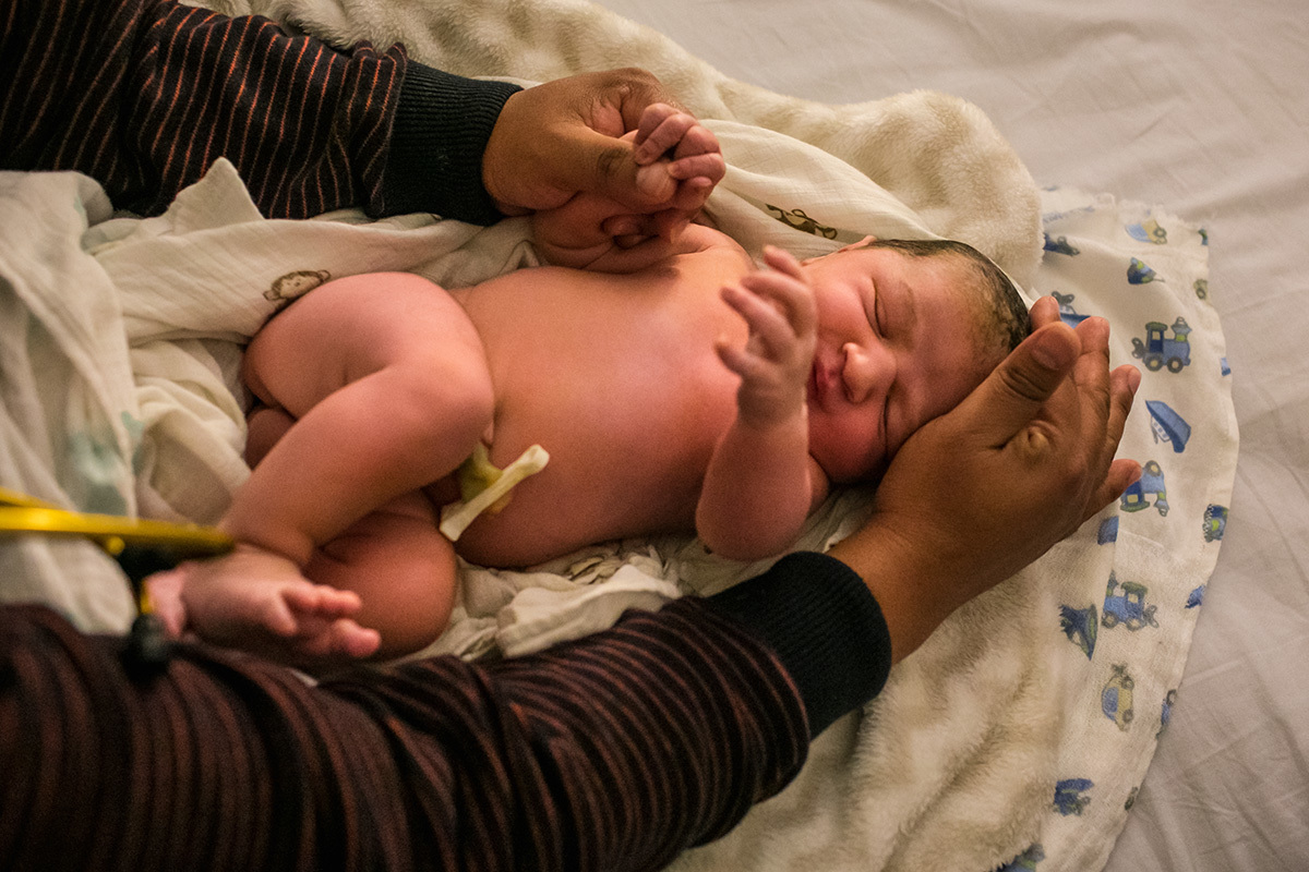 recém-nascido recebendo seu primeiro exame após o nascimento no quarto de seus pais