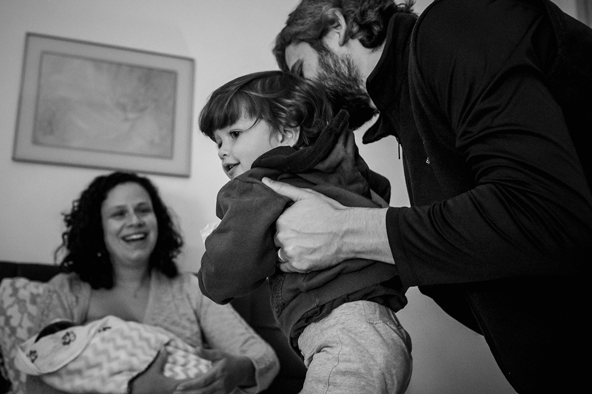 filho do meio do casal sendo apresentado ao caçula que acabou de nascer