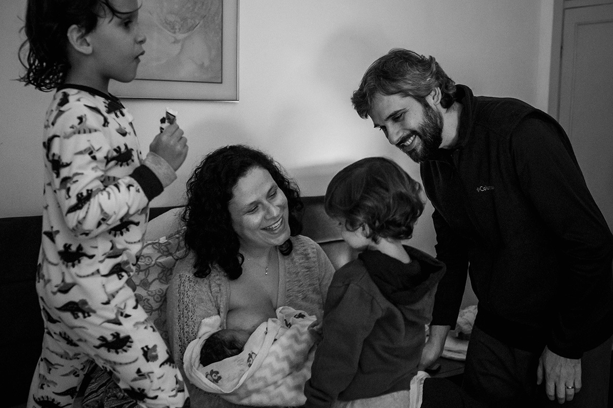 pais e seus dois filhos mais velhos contemplando o irmão caçula que acabou de nascer, por Adriana costa