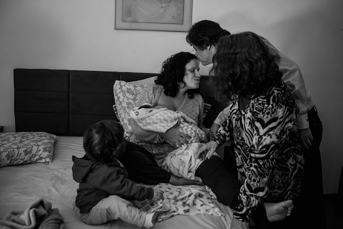 mulher recebendo seus pais para visitar seu filho caçula que acabou de nascer em sua própria casa, em foto de Adriana Costa