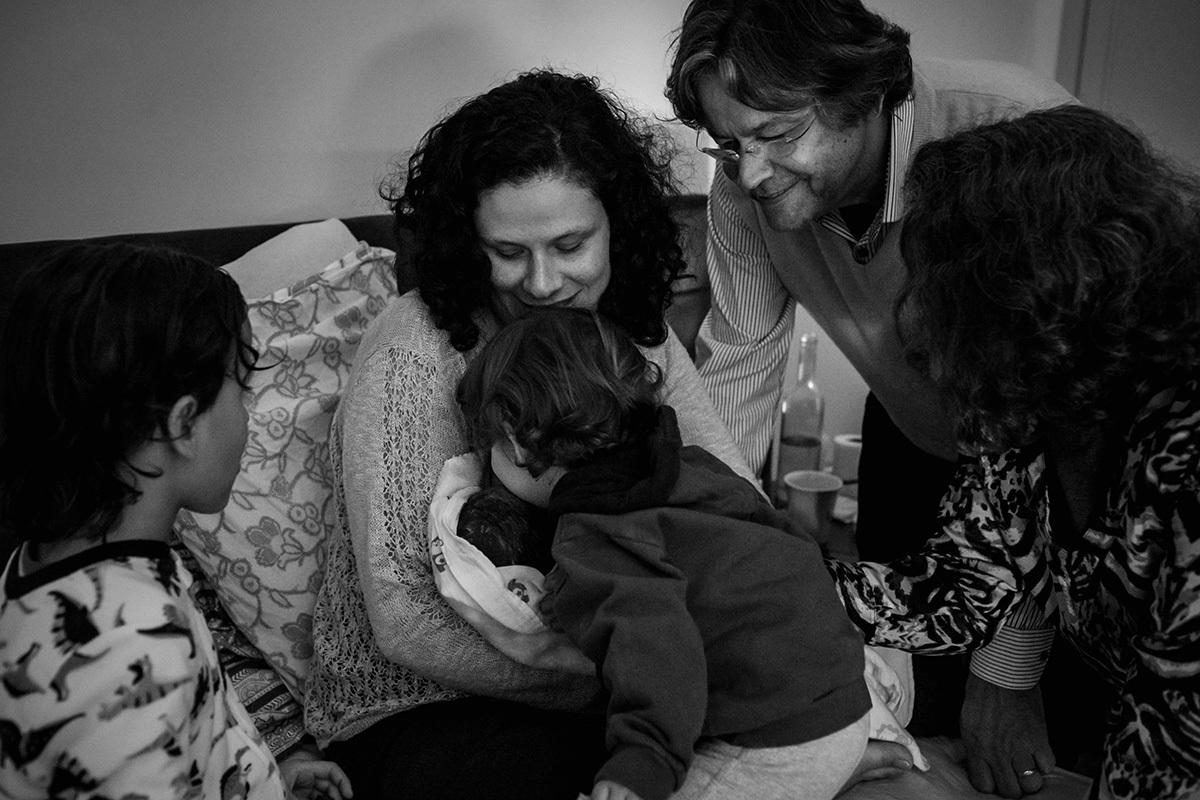 filho do meio do casal beijando seu irmão caçula que acabou de nascer