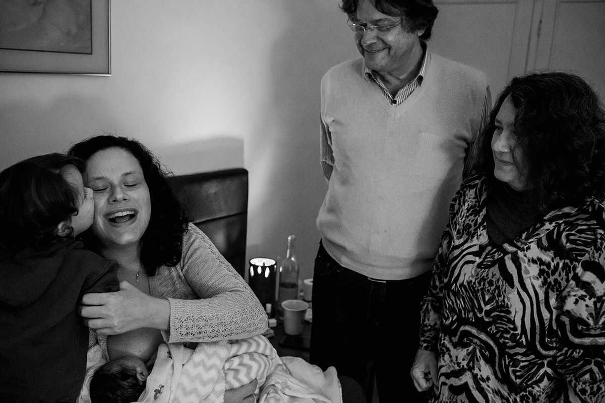 Adriana costa documenta criança beijando sua mãe que está com seu irmão recém nascido no colo ao lado dos seus avós