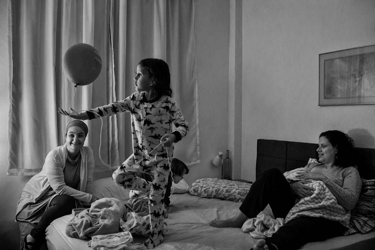 crianças brincam com balão na cama com a mãe no dia que o caçula nasceu