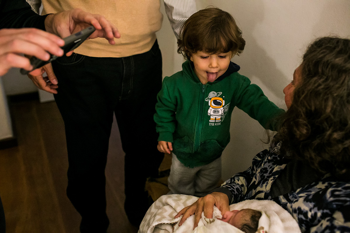 menino imita seu irmão que nasceu colocando a língua para fora enquanto seu pai o fotografa
