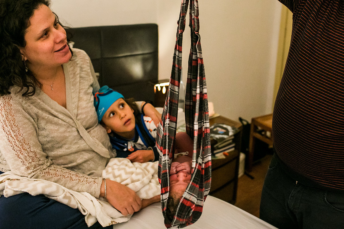 menino observa com sua mãe seu irmão que nasceu sendo pesado, em uma foto de Adriana Costa