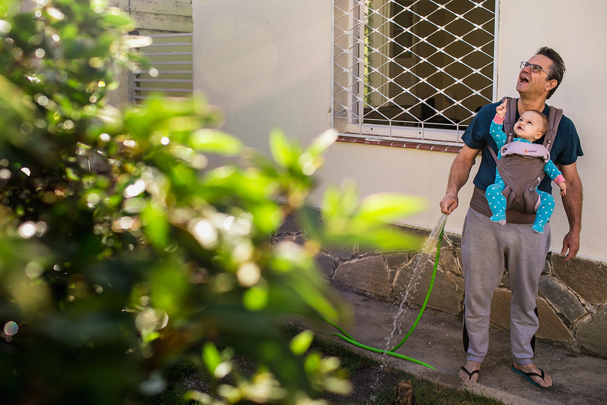 pai molhando o jardim com sua bebê de um ano, por Adriana Costa