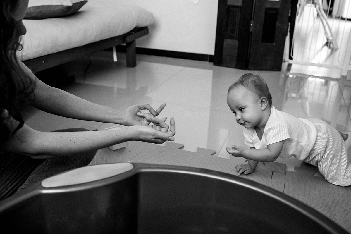 mãe chama sua bebê que está engatinhando