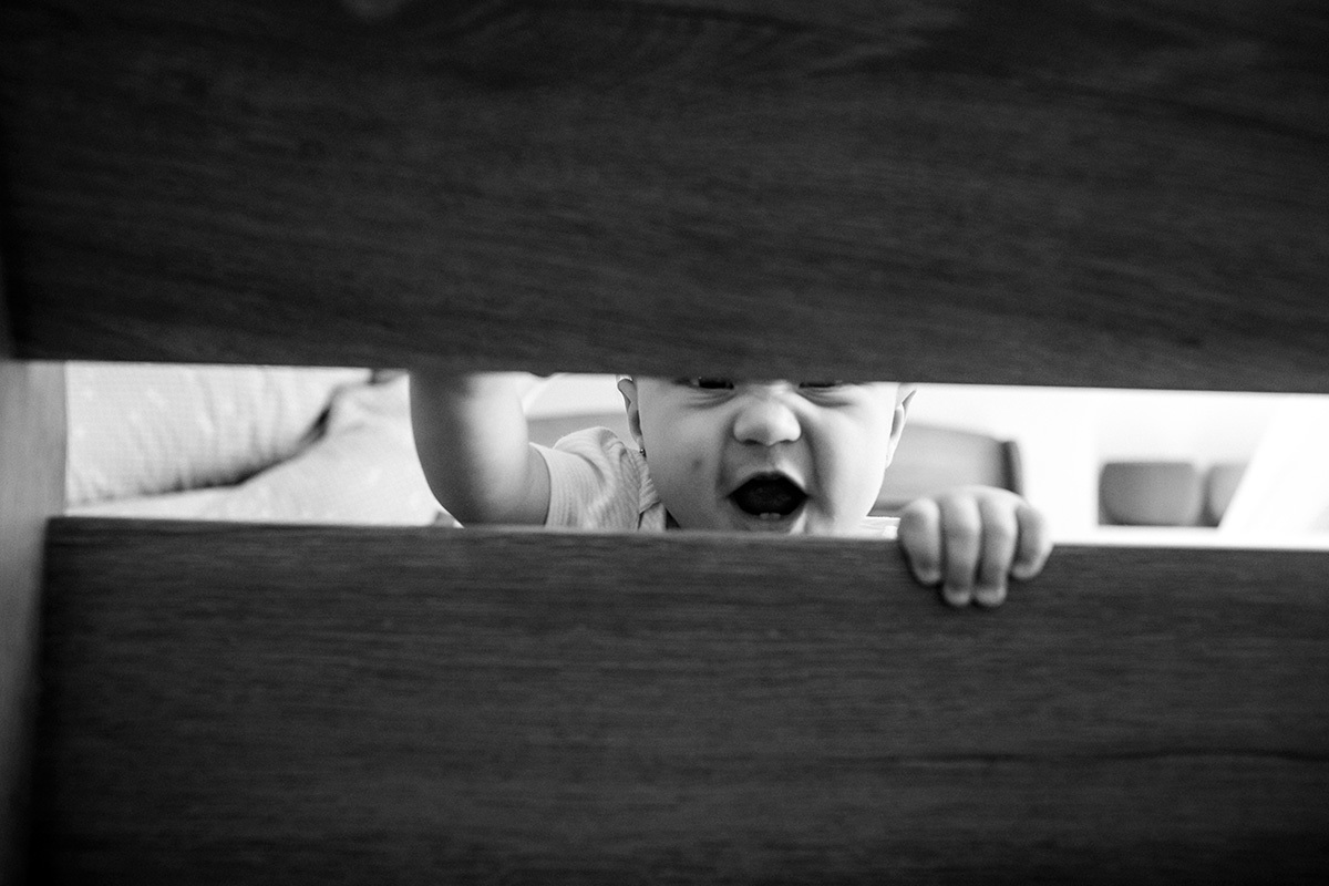 bebê brinca pela fresta do berço