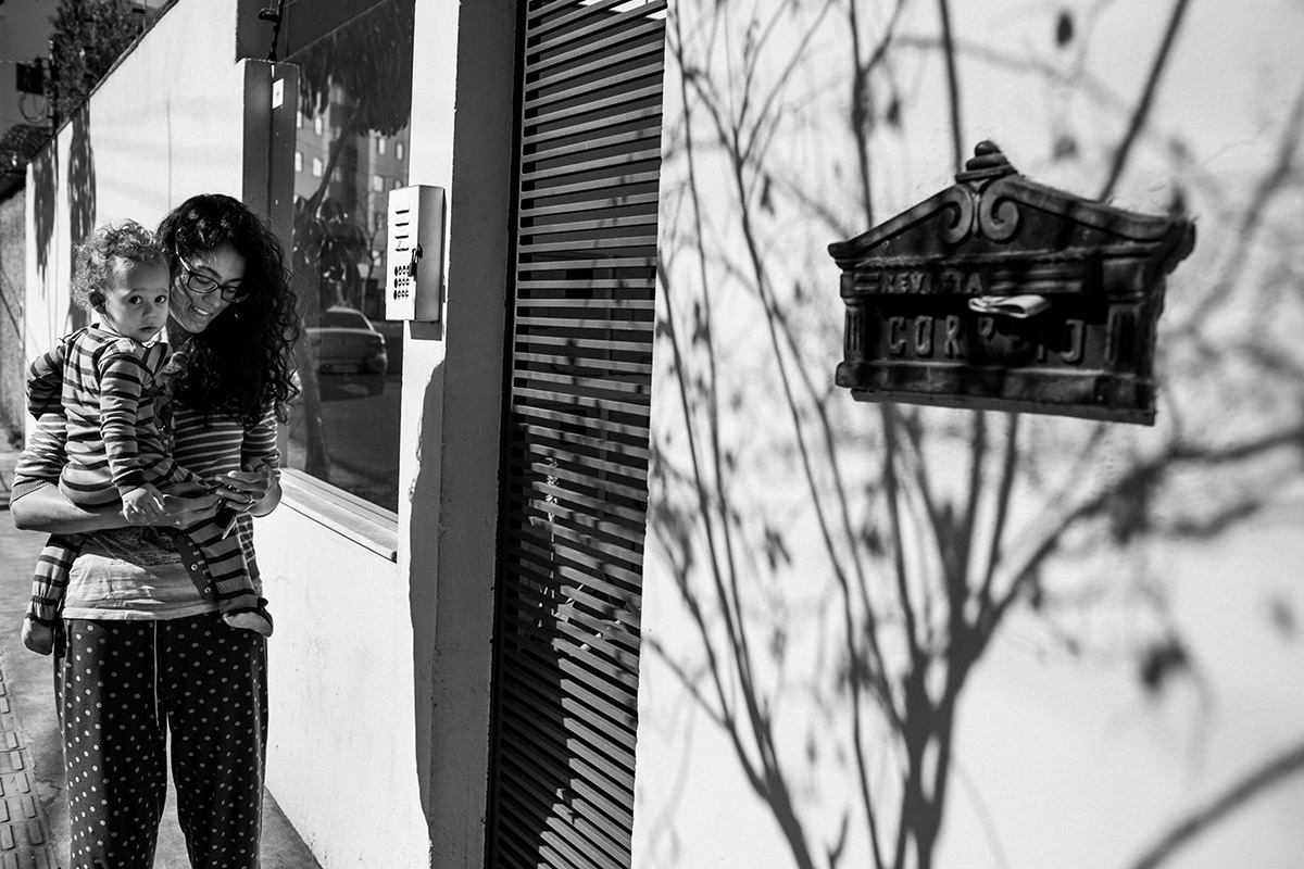 mãe e filho voltando para casa após um passeio na rua pela manhã durante um acompanhamento documental da família feito por Adriana Costa