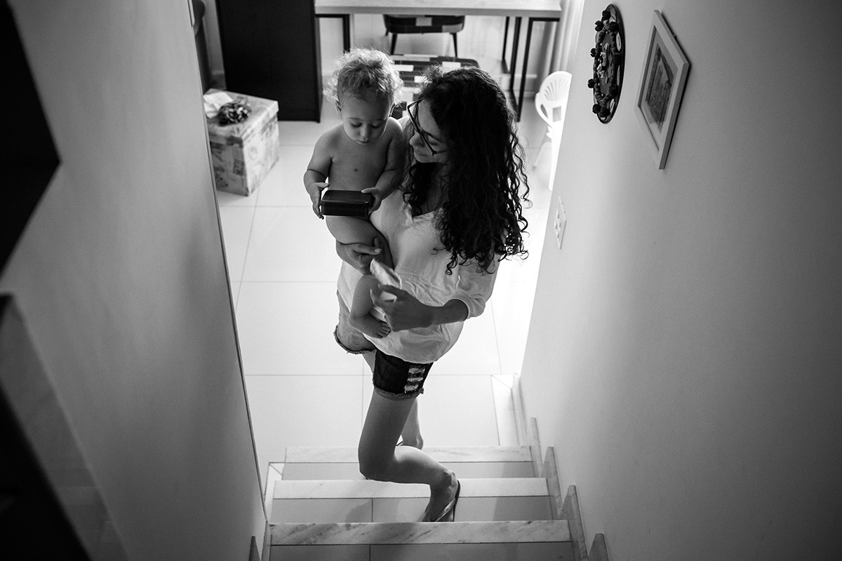 mãe leva seu filho para tomar banho no andar de cima da casa 