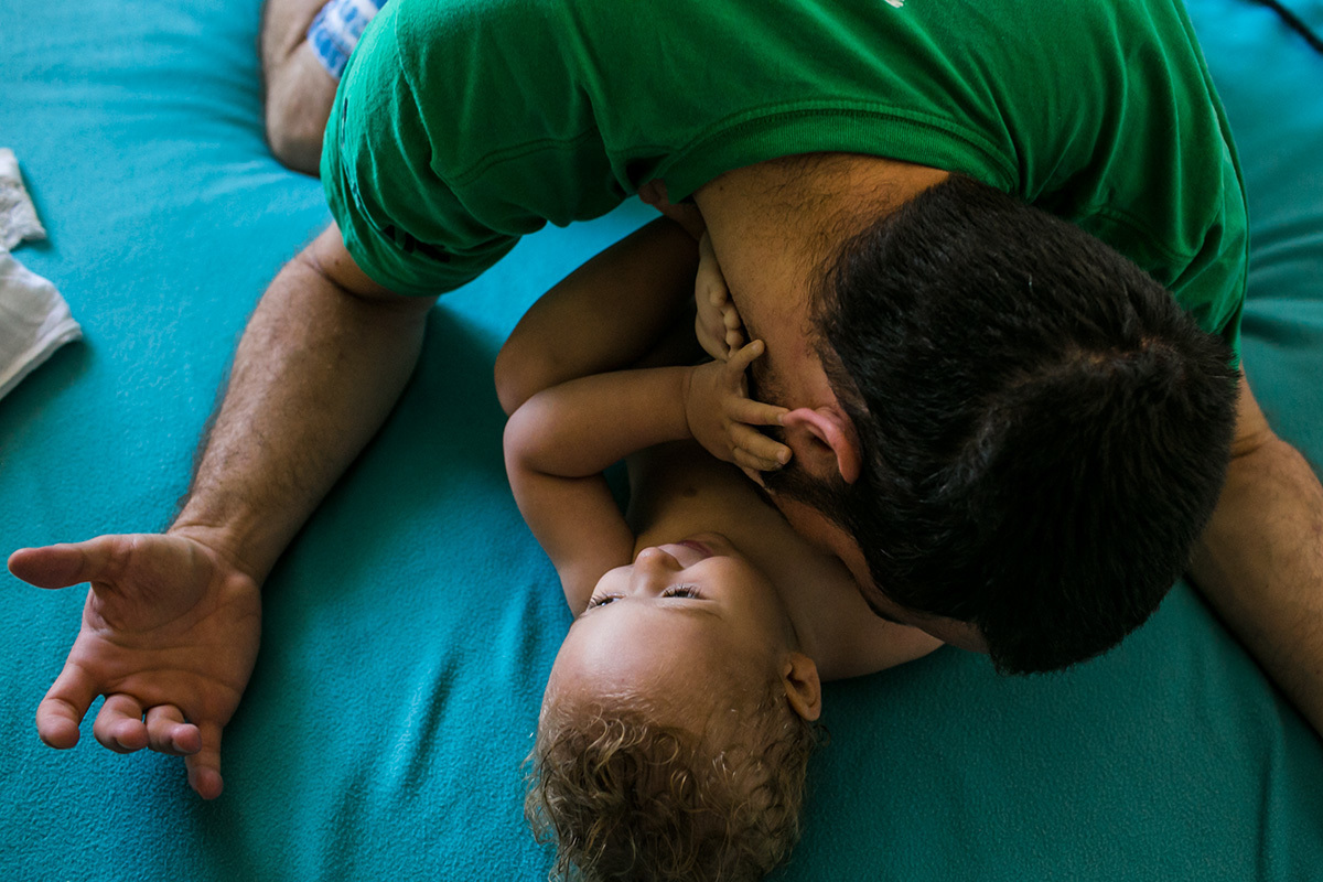 pai brinca com seu bebê de um ano na cama