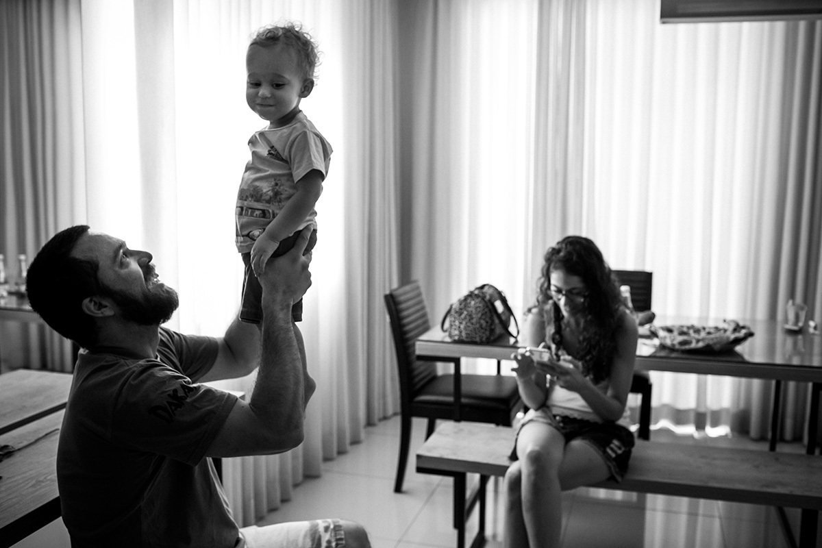 menino faz cara de levado quando seu pai o levanta pelas pernas em direção ao teto