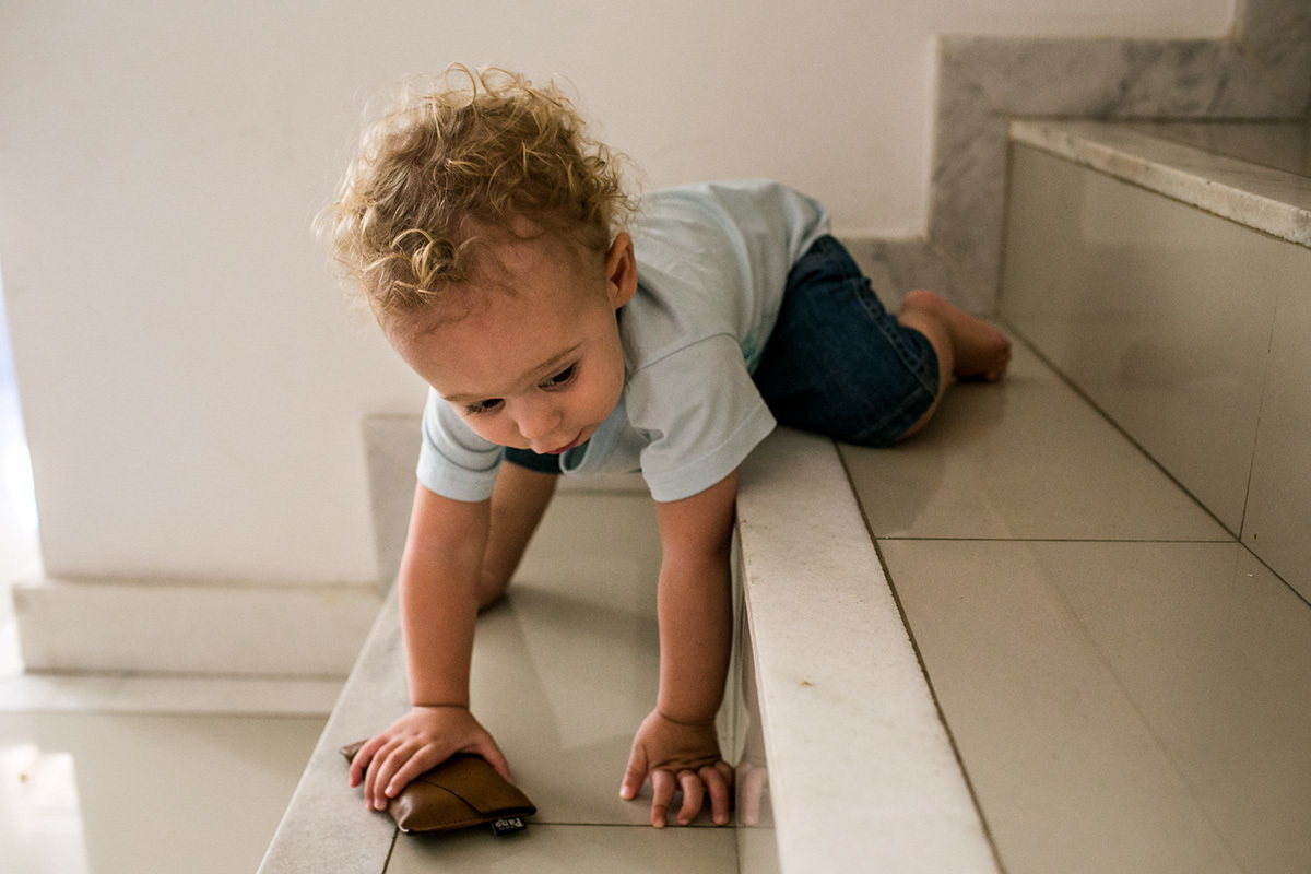 menino de um ano tentando subir a escada, por Adriana Costa