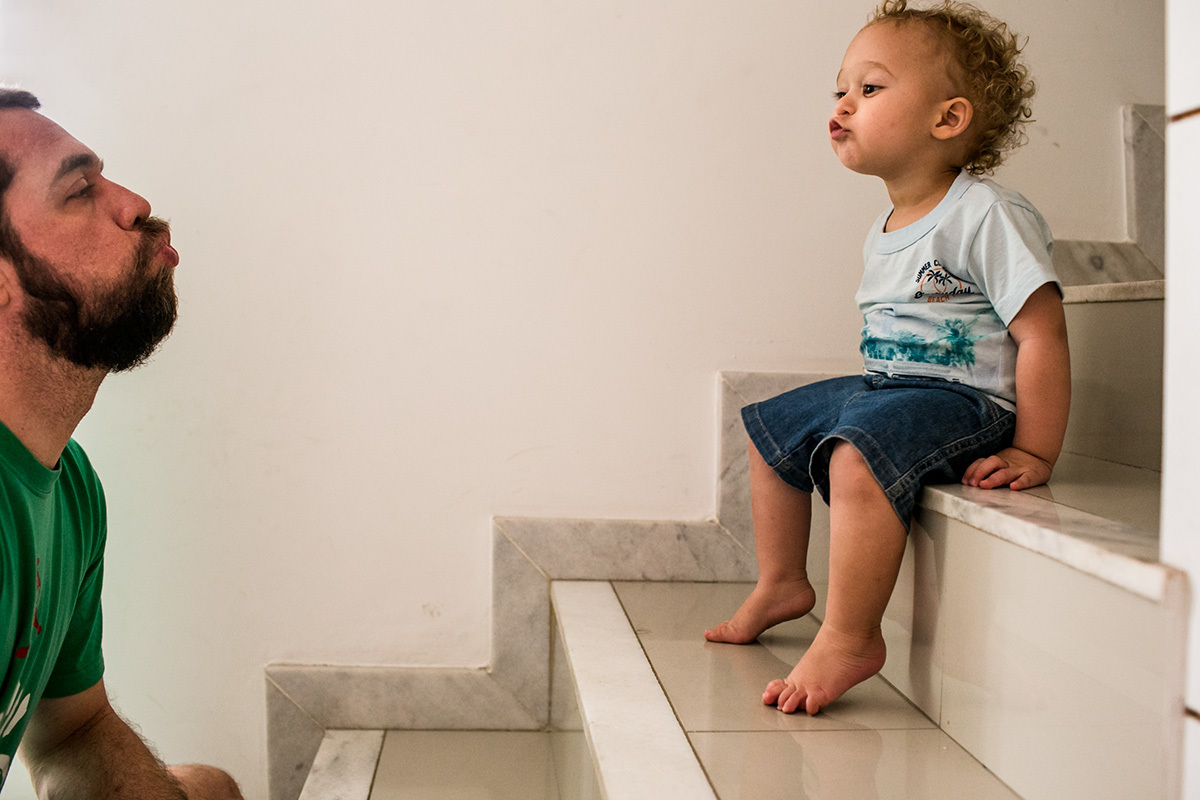 menino de um ano mandando beijo para o seu pai do alto da escada