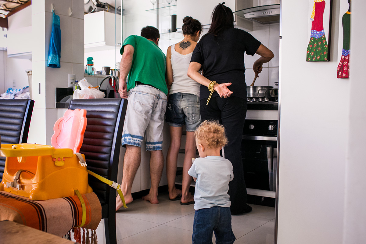menino na cozinha enquanto seus pais e sua avó preparam o almoço