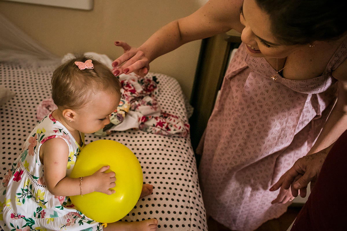 mãe terminando de arrumar sua filha para o aniversário de se 1 aninho