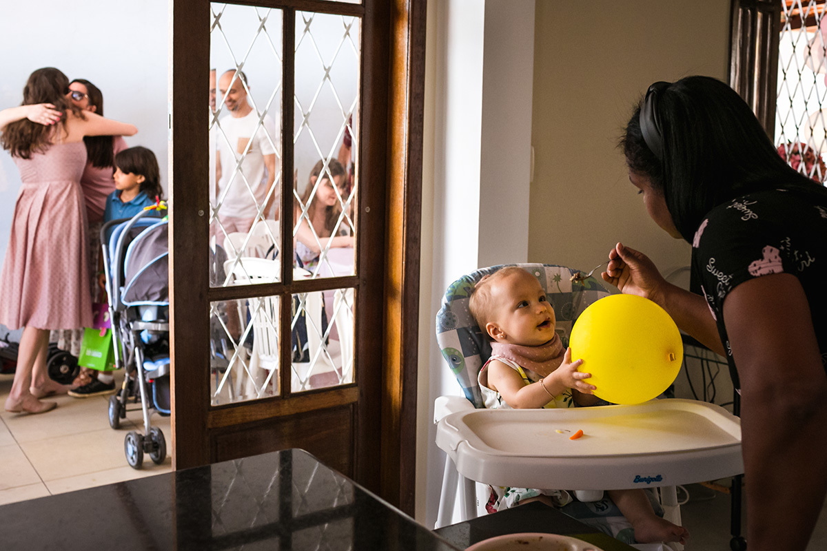 Adriana Costa fotografou a mãe recebendo os convidados para o aniversário de 1 ano de sua filha, enquanto sua filha almoça segurando um balão