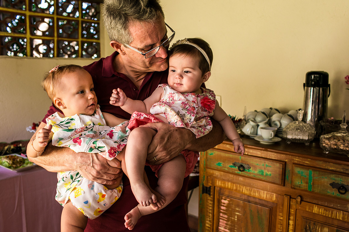 pai segura sua filha durante sua festa de um ano junto com sua neta de mesma idade