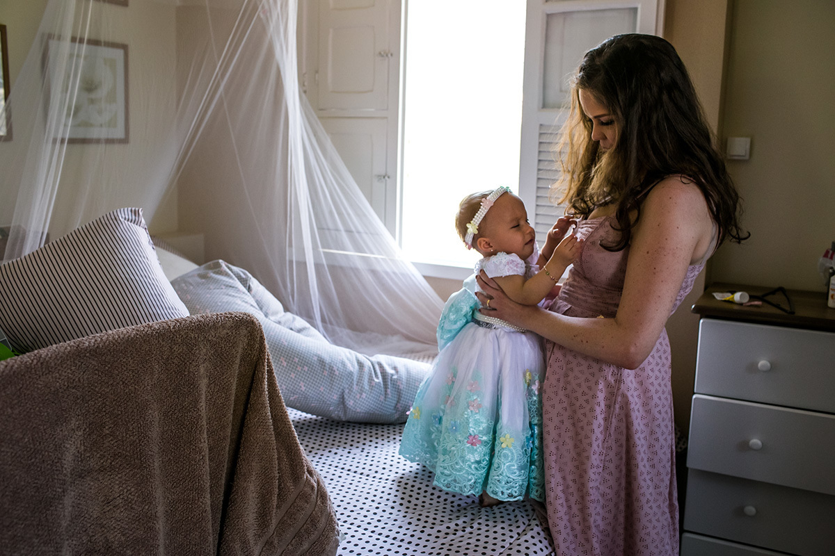 mãe preparando sua filha para retirar o vestido de sua festa de 1 ano e deixá-la mias à vontade