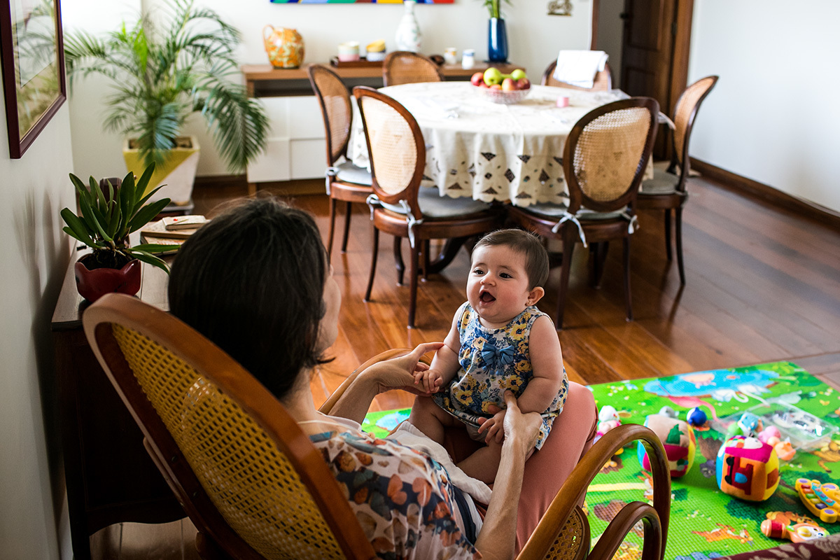 mãe brincando com sua filha na cadeira de balanço que foi da sua avô, em foto de Adriana Costa