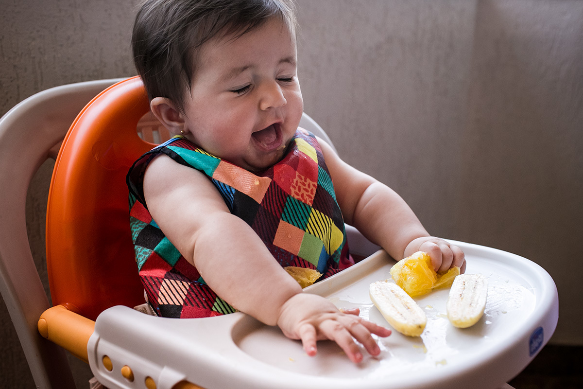 bebê fazendo careta ao comer laranja, por Adriana Costa