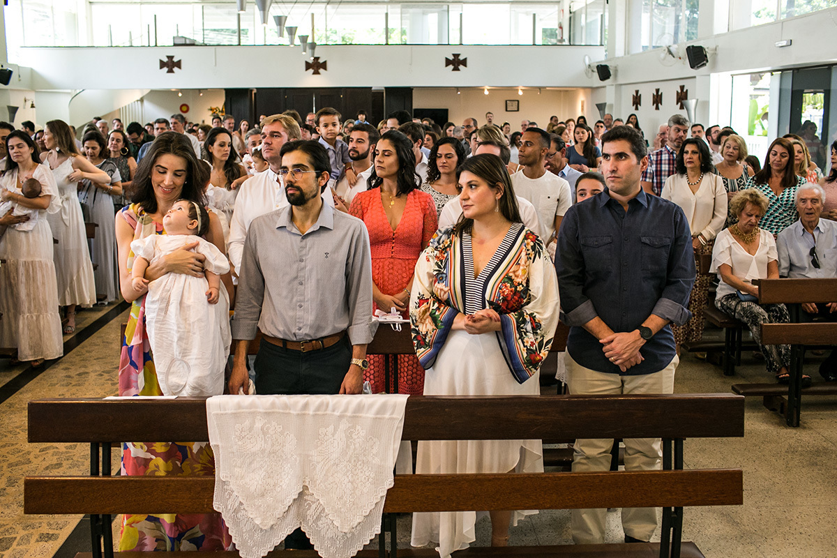 família em pé na igreja recebendo as orações do batismo