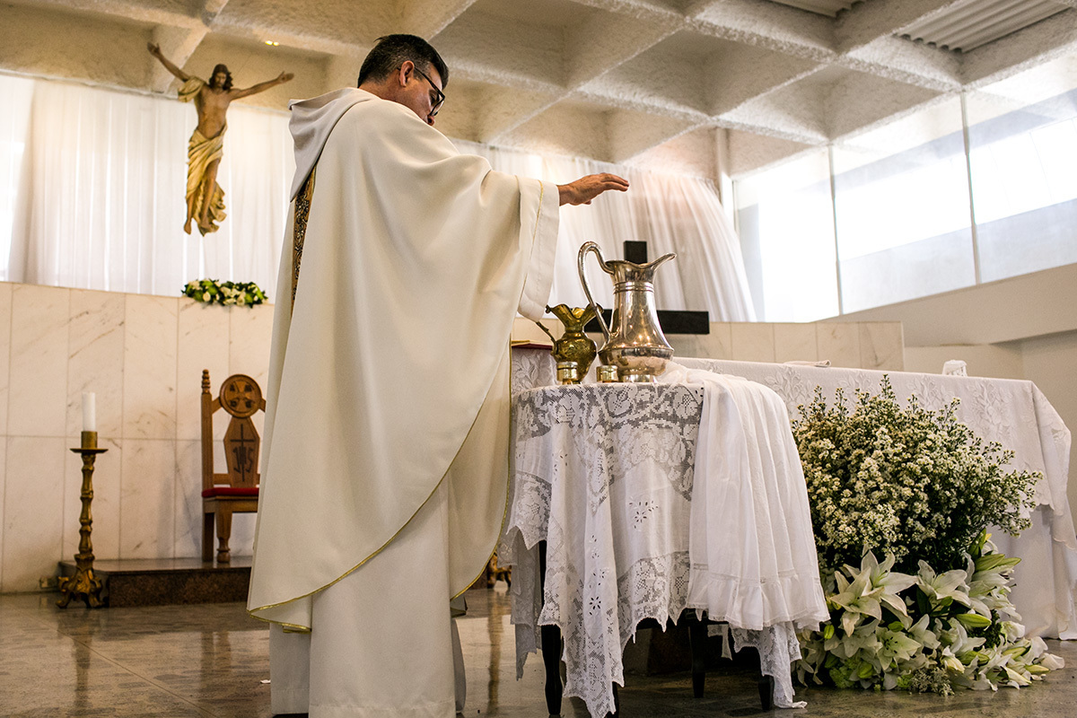 padre abençoando a água que será usada na pia batismal
