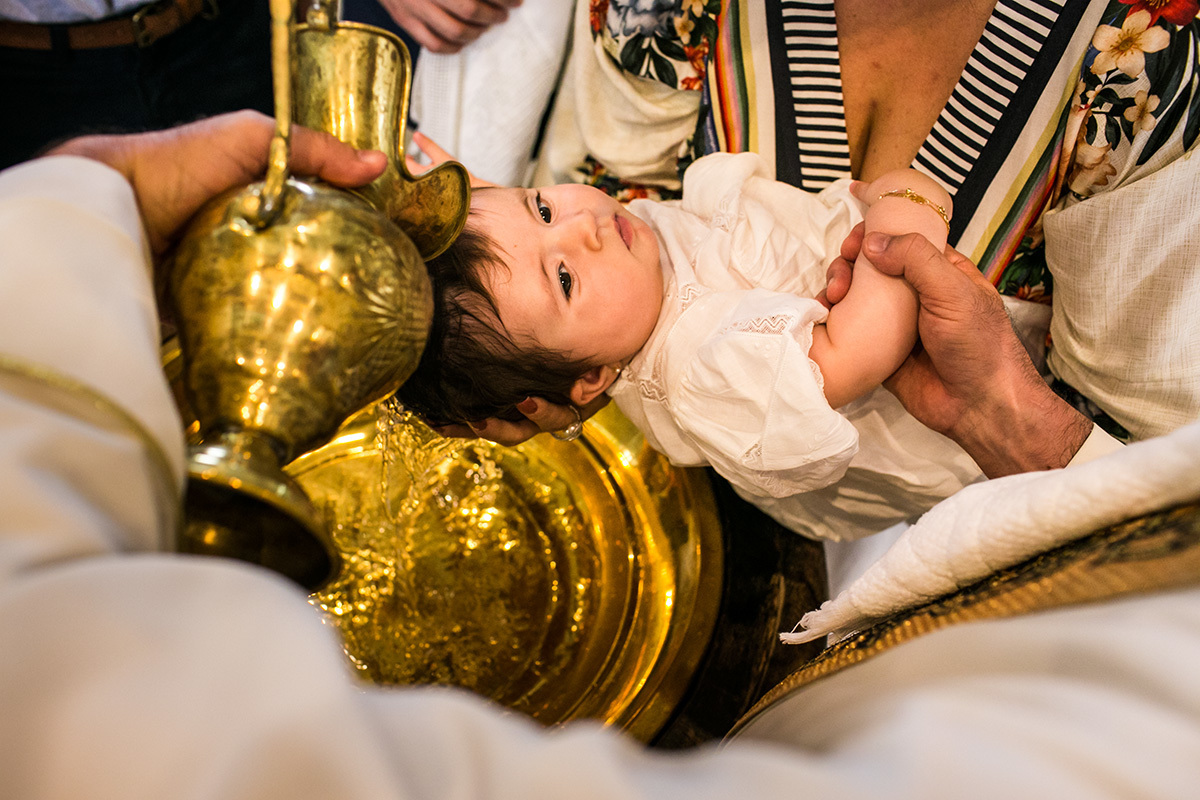 Adriana Costa fotografou bebê recebendo a água sagrada na cabeça na pia batismal