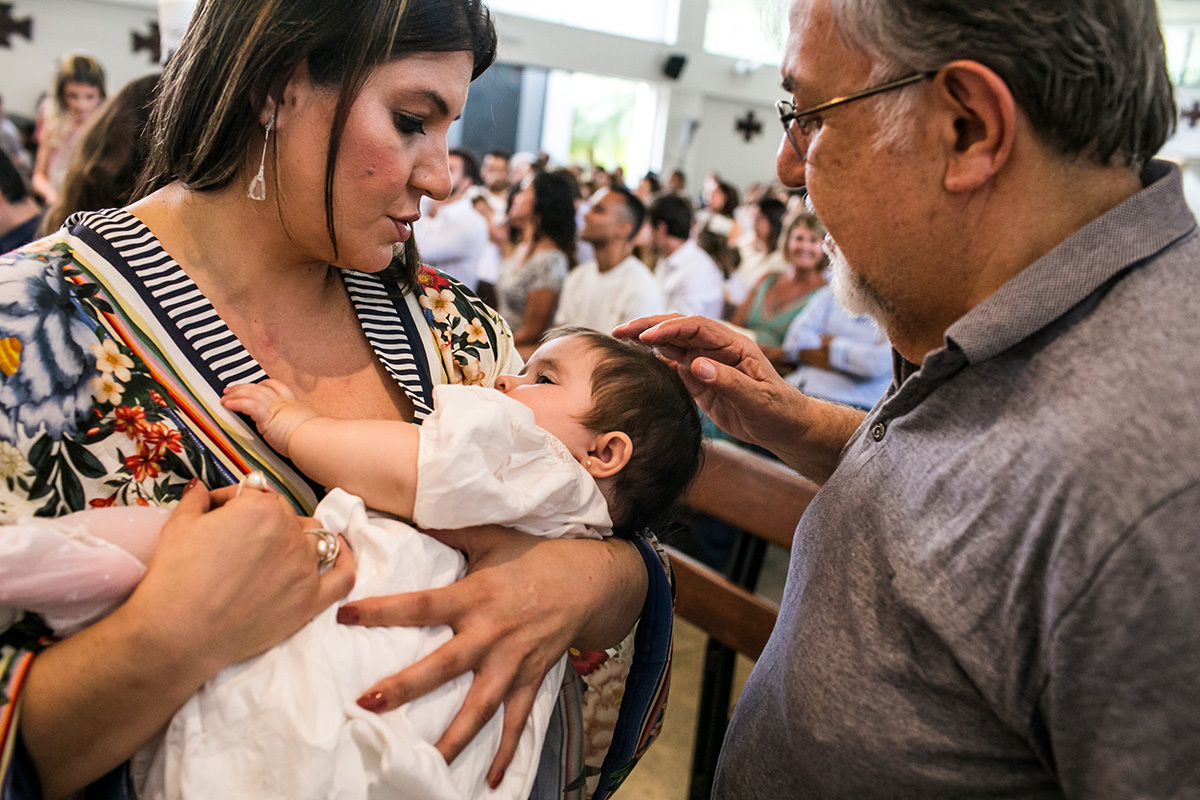 avô faz carinho na neta após ela sair da pia batismal