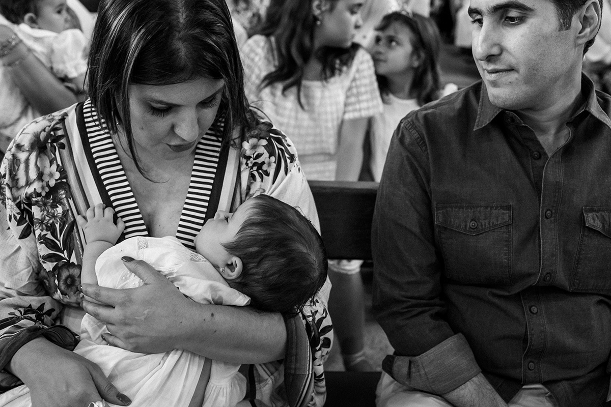 madrinha faz sua afilhada dormir durante a cerimônia de batismo, em foto de Adriana Costa