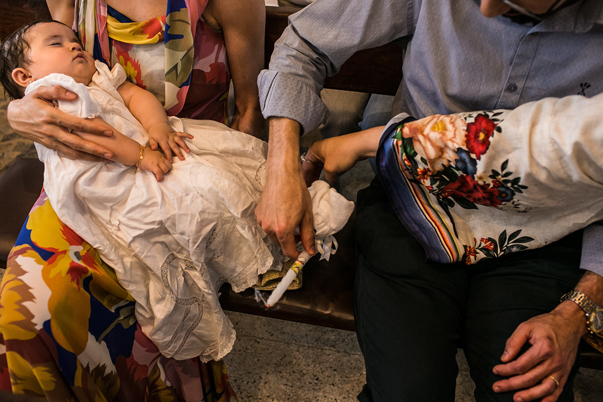 bebê dorme enquanto seus pais apagam a vela da cerimônia de batismo, por Adriana Costa