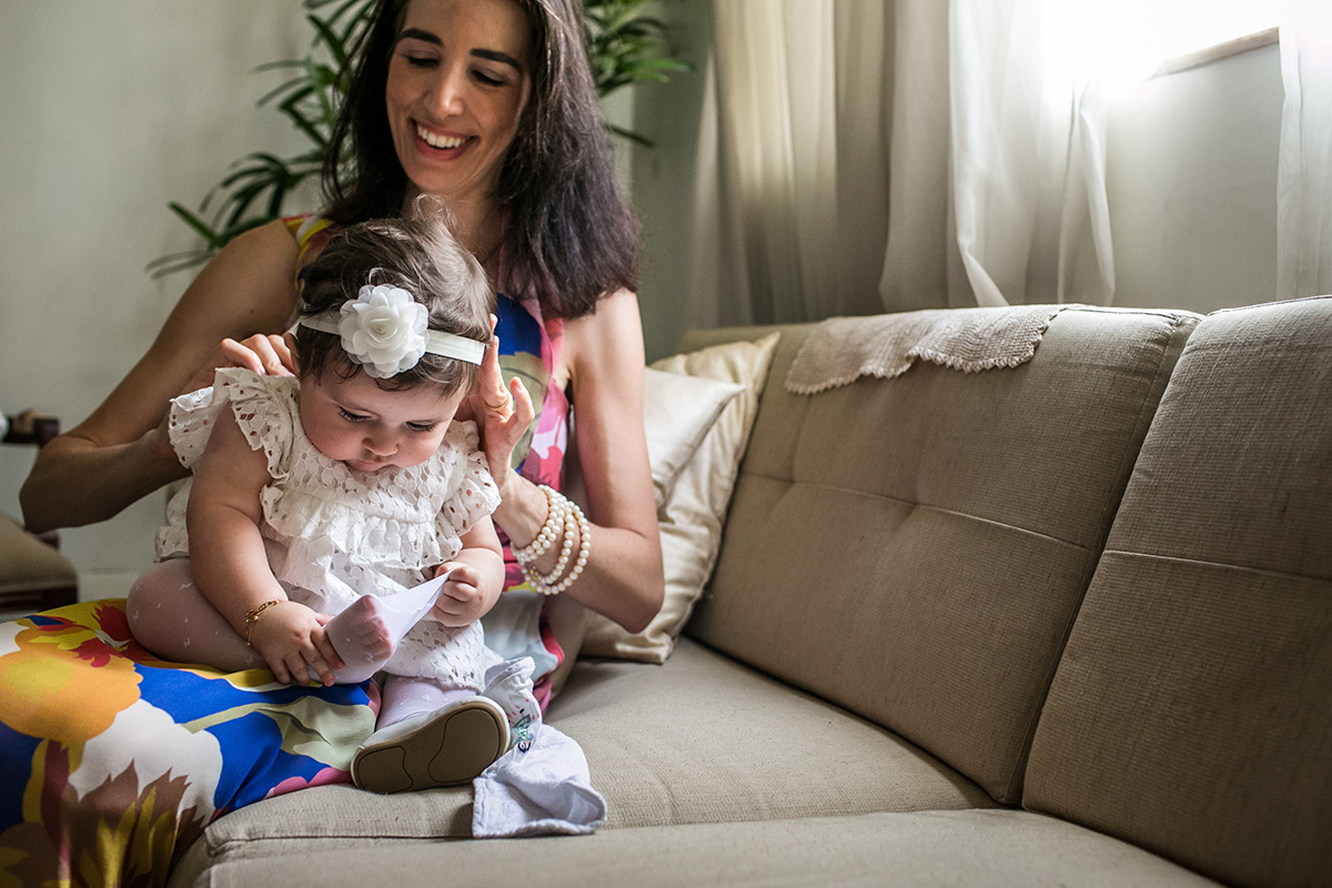 bebê brincando com sua meia calça no dia do batizado, em foto de Adriana Costa