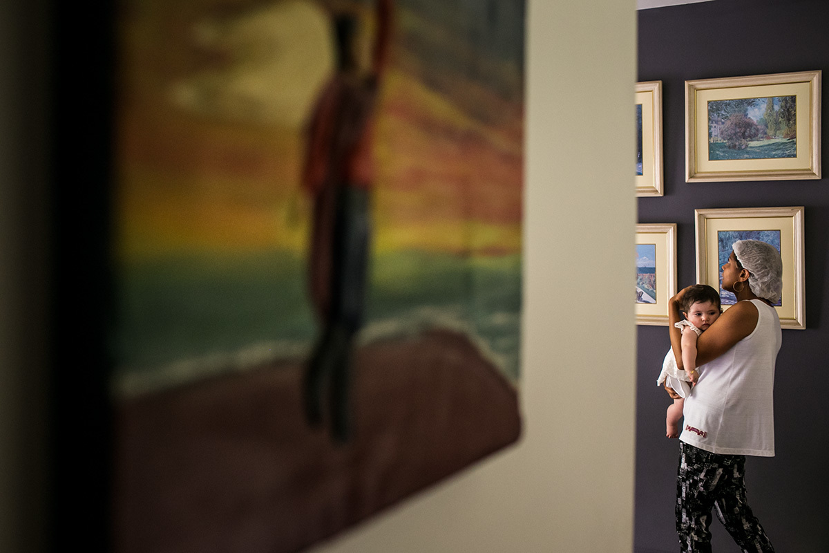 bebê sendo ninada pela funcionária da família no dia do seu batizado, em foto de Adriana Costa