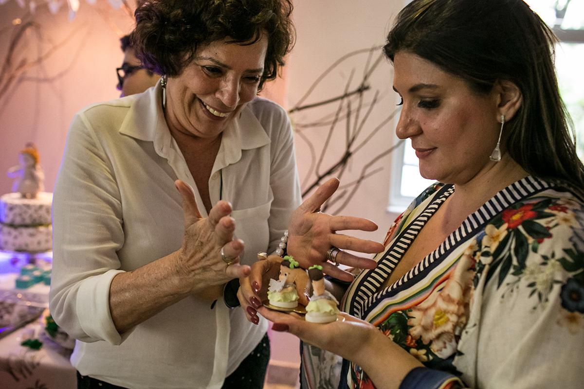 Foto de Adriana Costa da avó admirando o docinho em forma de anjo da festa de batizado da sua neta