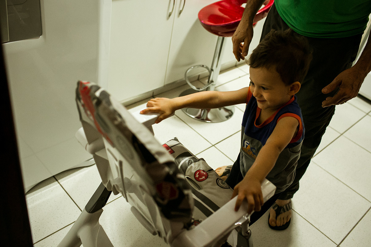 criança subindo na cadeirinha para jantar