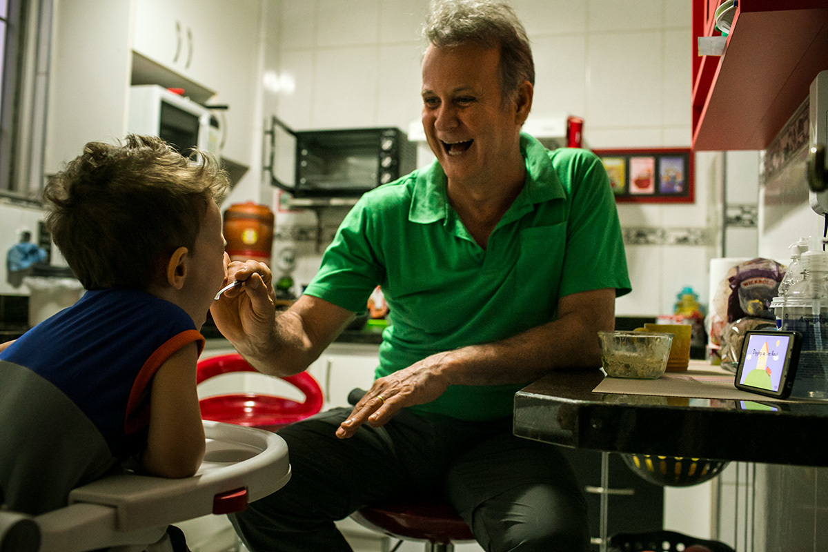 pai feliz dando jantar para o filho, por adrianacostafotos