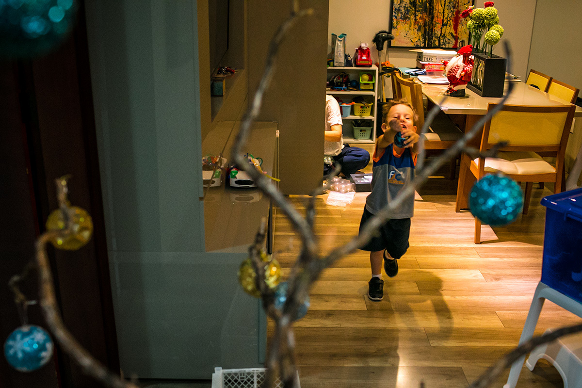 menino corre feliz pela sala de sua casa para enfeitar sua árvore de Natal