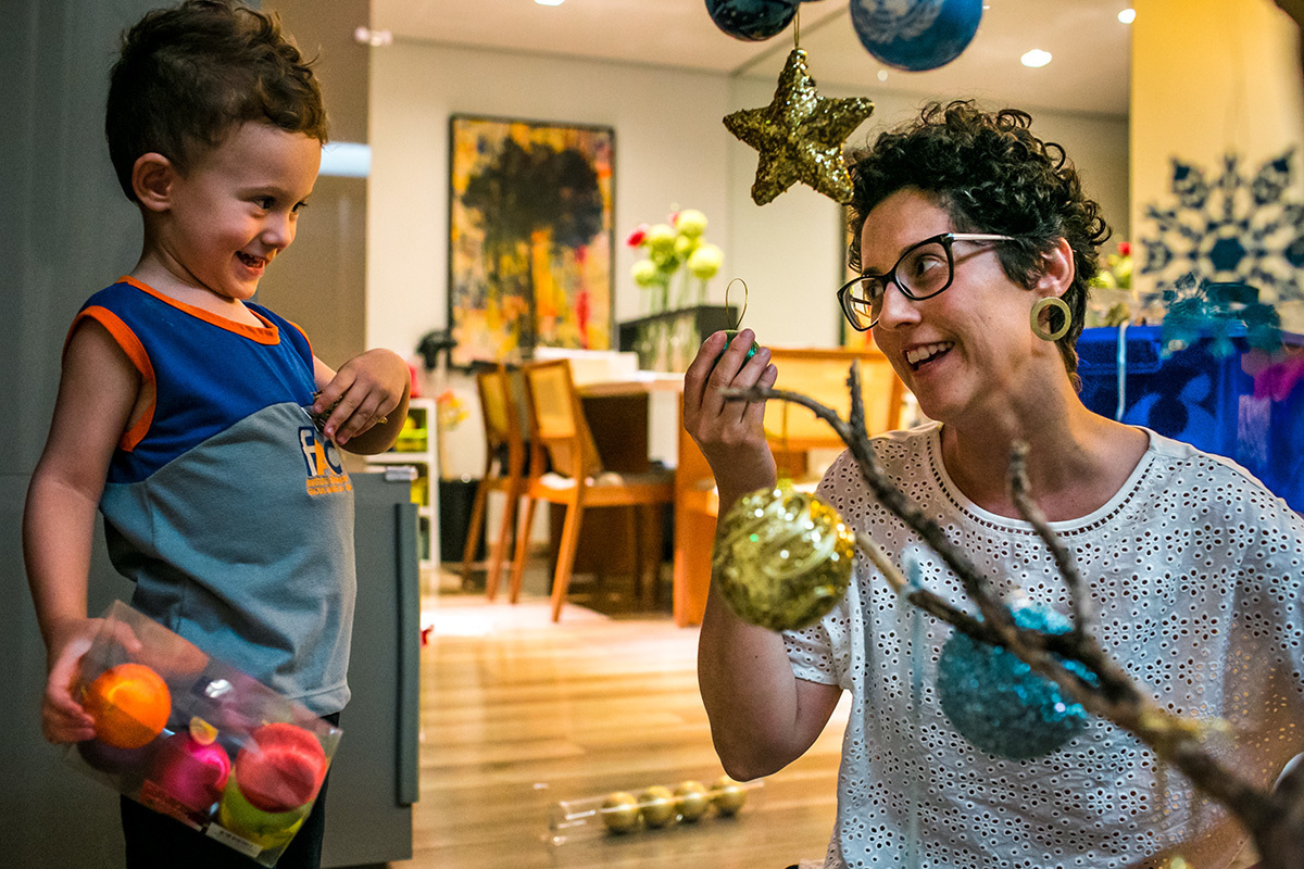 mãe brinca com o filho enquanto monta a árvore de Natal, em foto de Adriana Costa