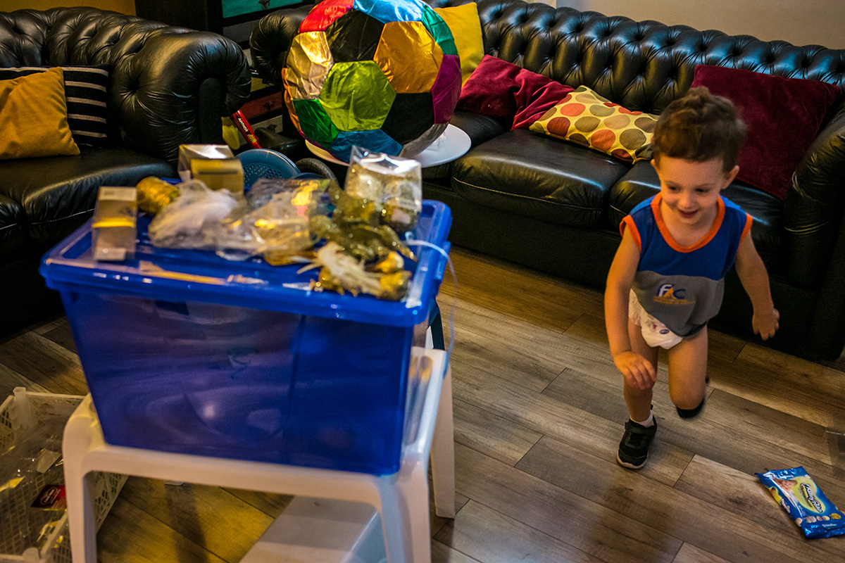 menino corre ao redor da mesa feliz por estar montando sua árvore de Natal