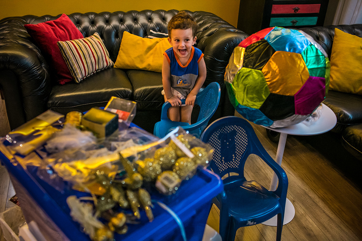 menino dá gargalhada se divertindo no dia de enfeitar a árvore de Natal