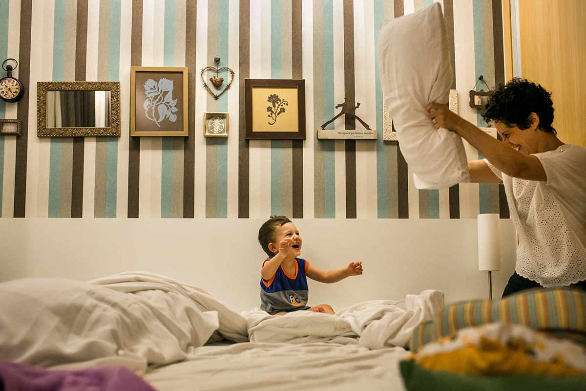 mãe brinca com o filho na sua cama, por Adriana Costa