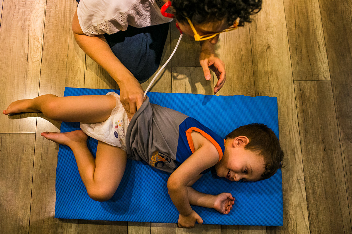 mãe brinca que está examinando o seu filho com brinquedos de médico