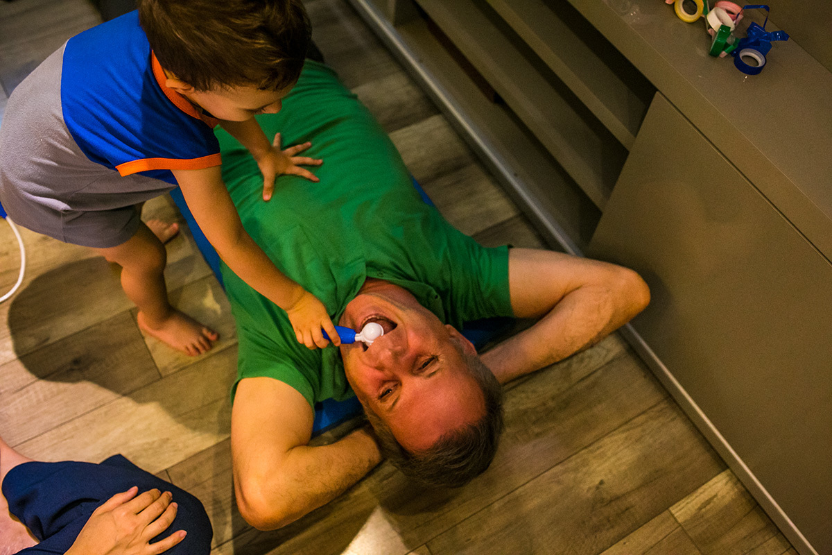 foto de Adriana Costa do menino brincando de examinar a garganta do seu pai como médico