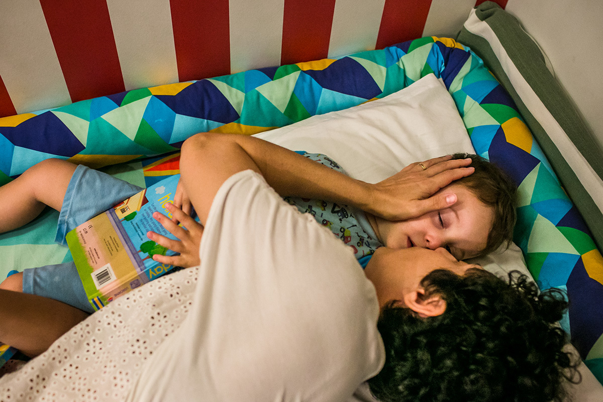mãe dá o beijo de boa noite no filho, em foto de Adriana Costa